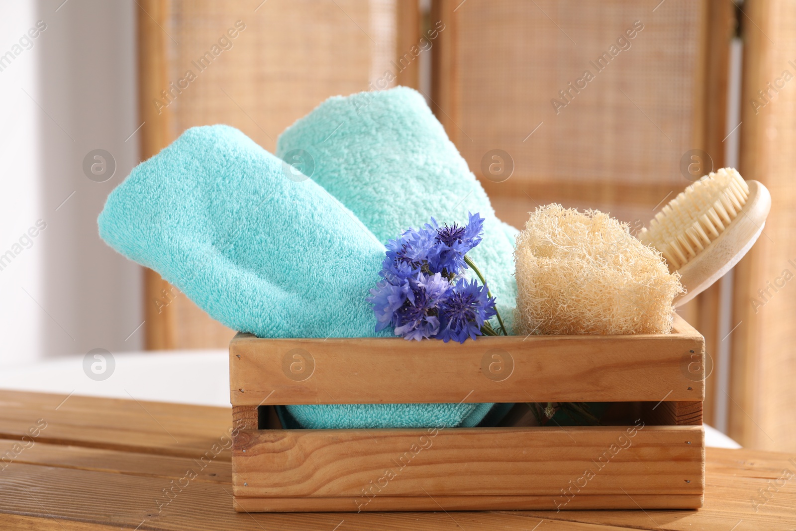 Soft towels, brush, loofah and flowers on wooden board indoors, closeup Photo of Soft towels, brush, loofah and flowers on wooden board indoors, closeup