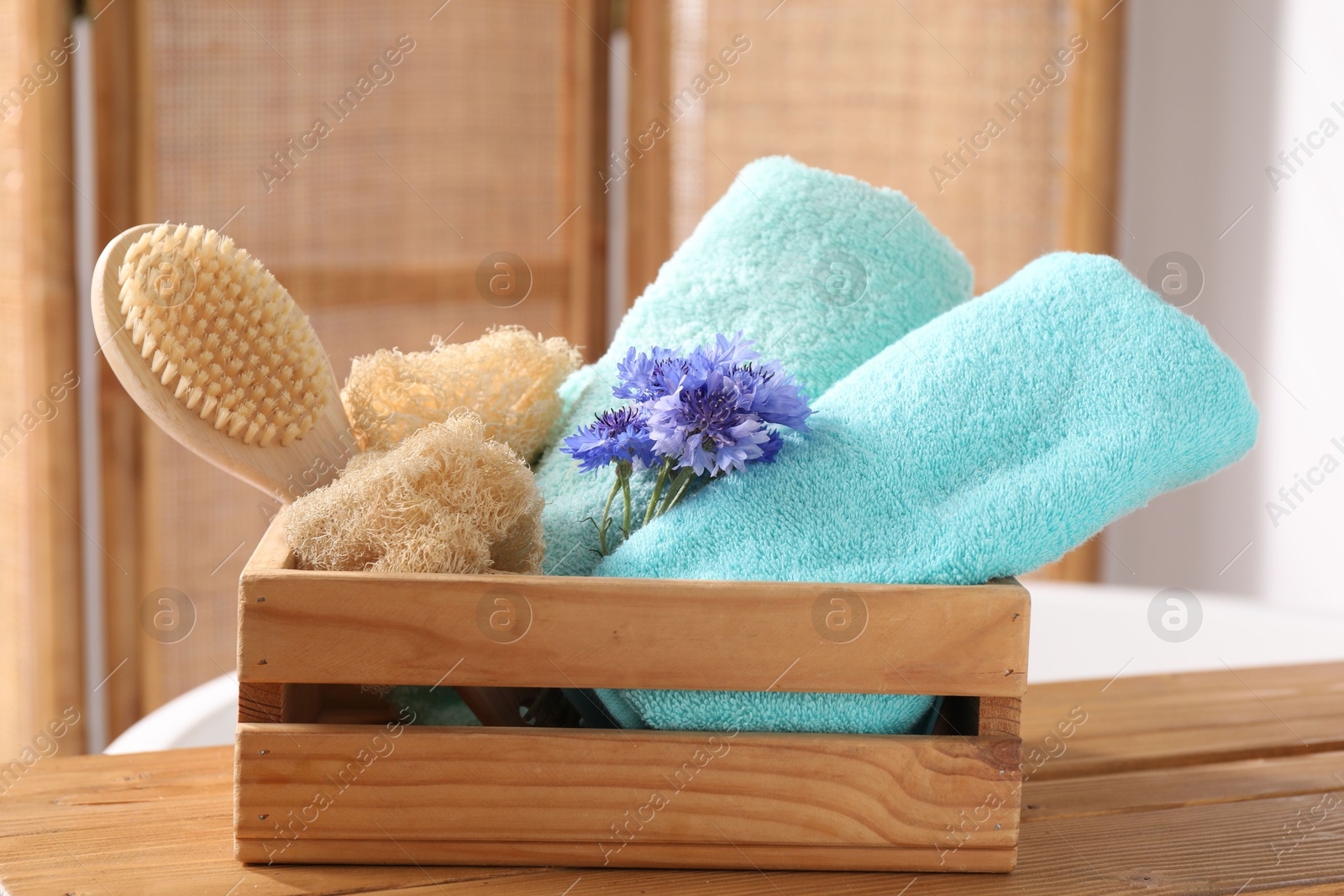 Soft towels, brush, loofah and flowers on wooden board indoors, closeup Photo of Soft towels, brush, loofah and flowers on wooden board indoors, closeup