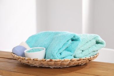 Photo of Soft towels, soap and sea salt on wooden board indoors, closeup
