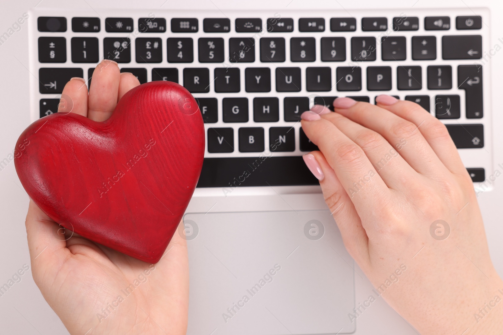 Online dating site. Woman with decorative heart using laptop, top view Photo of Online dating site. Woman with decorative heart using laptop, top view