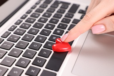 Photo of Online dating site. Woman touching red heart on laptop, closeup