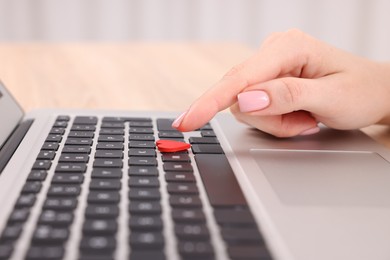 Photo of Online dating site. Woman touching red heart on laptop at table, closeup