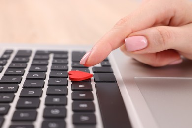 Photo of Online dating site. Woman touching red heart on laptop at table, closeup