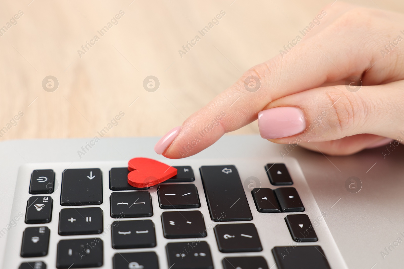 Online dating site. Woman touching red heart on laptop at table, closeup Photo of Online dating site. Woman touching red heart on laptop at table, closeup