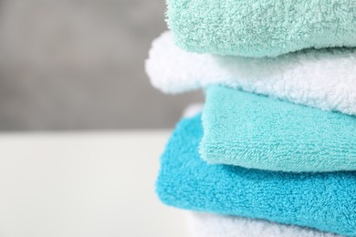 Photo of Stack of colorful towels on white table, closeup. Space for text