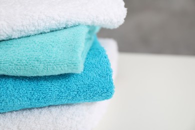 Photo of Stack of colorful towels on white table, closeup. Space for text
