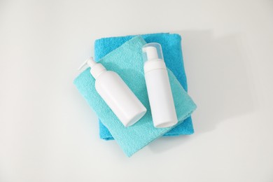 Photo of Stack of colorful towels and cosmetic products on white table, top view