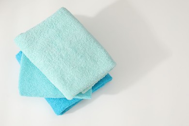 Photo of Stack of colorful towels on white table, top view. Space for text