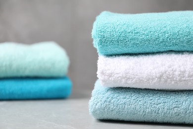 Photo of Stacks of soft towels on grey marble table, closeup. Space for text