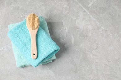 Photo of Stack of soft towels and brush on grey marble table, top view. Space for text