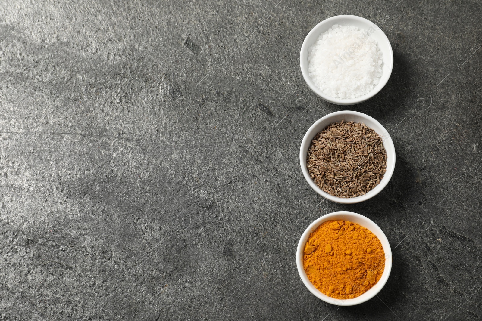 Photo of Different aromatic spices on grey table, flat lay. Space for text