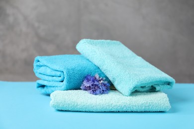 Photo of Soft towels and flowers on light blue table