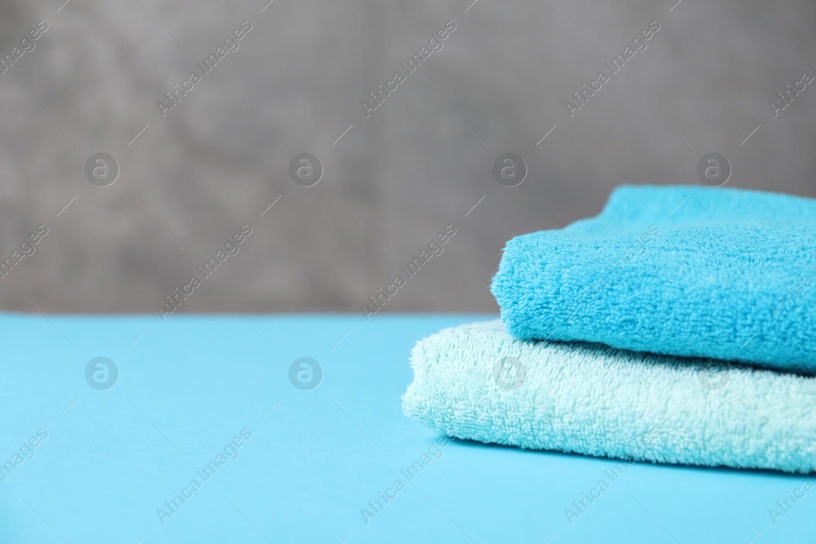 Photo of Soft towels on light blue table, closeup. Space for text