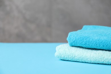 Photo of Soft towels on light blue table, closeup. Space for text