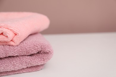 Photo of Stack of colorful towels on white table, closeup. Space for text