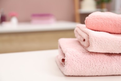 Photo of Stack of colorful towels on white table in bathroom, closeup. Space for text