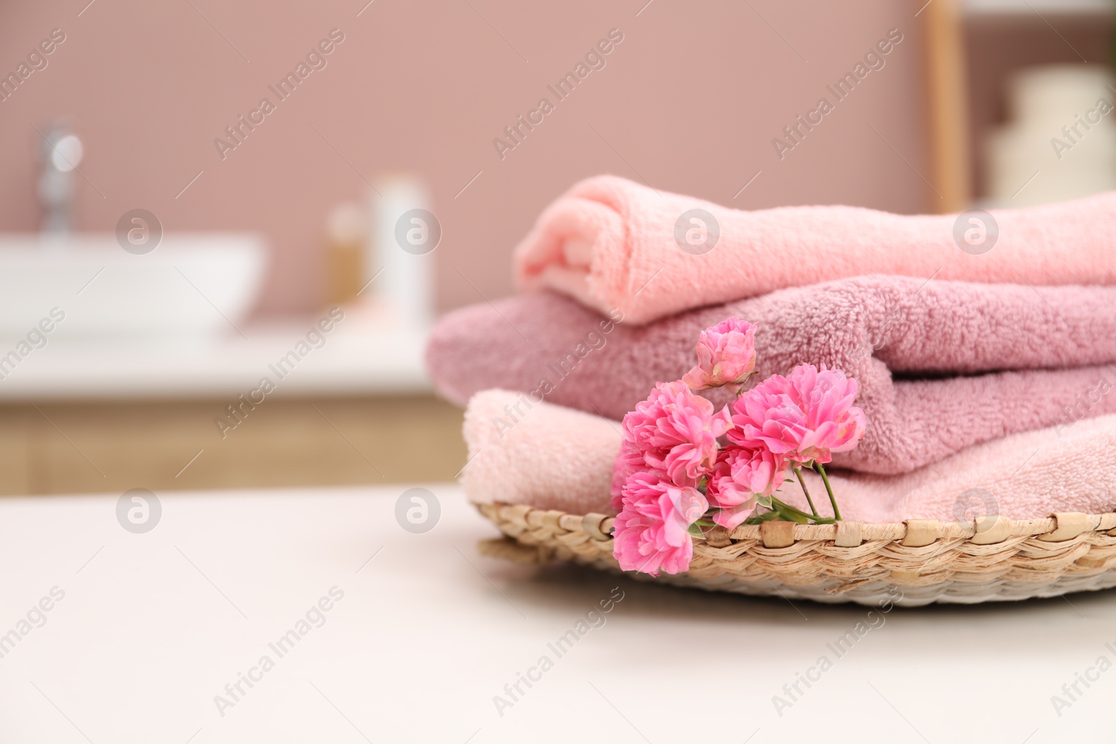 Colorful towels and flowers on white table in bathroom, closeup. Space for text Photo of Colorful towels and flowers on white table in bathroom, closeup. Space for text