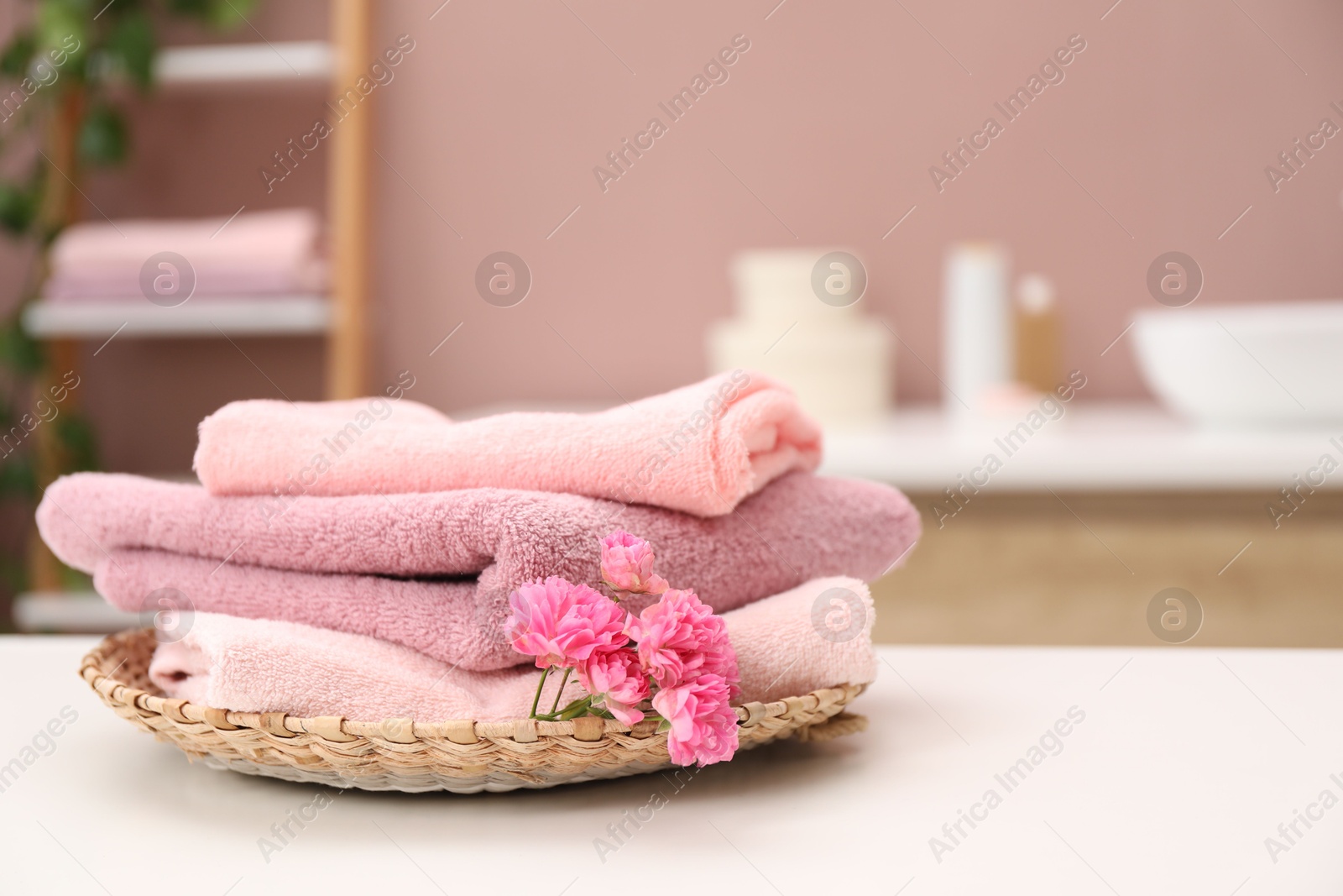 Colorful towels and flowers on white table in bathroom, closeup. Space for text Photo of Colorful towels and flowers on white table in bathroom, closeup. Space for text