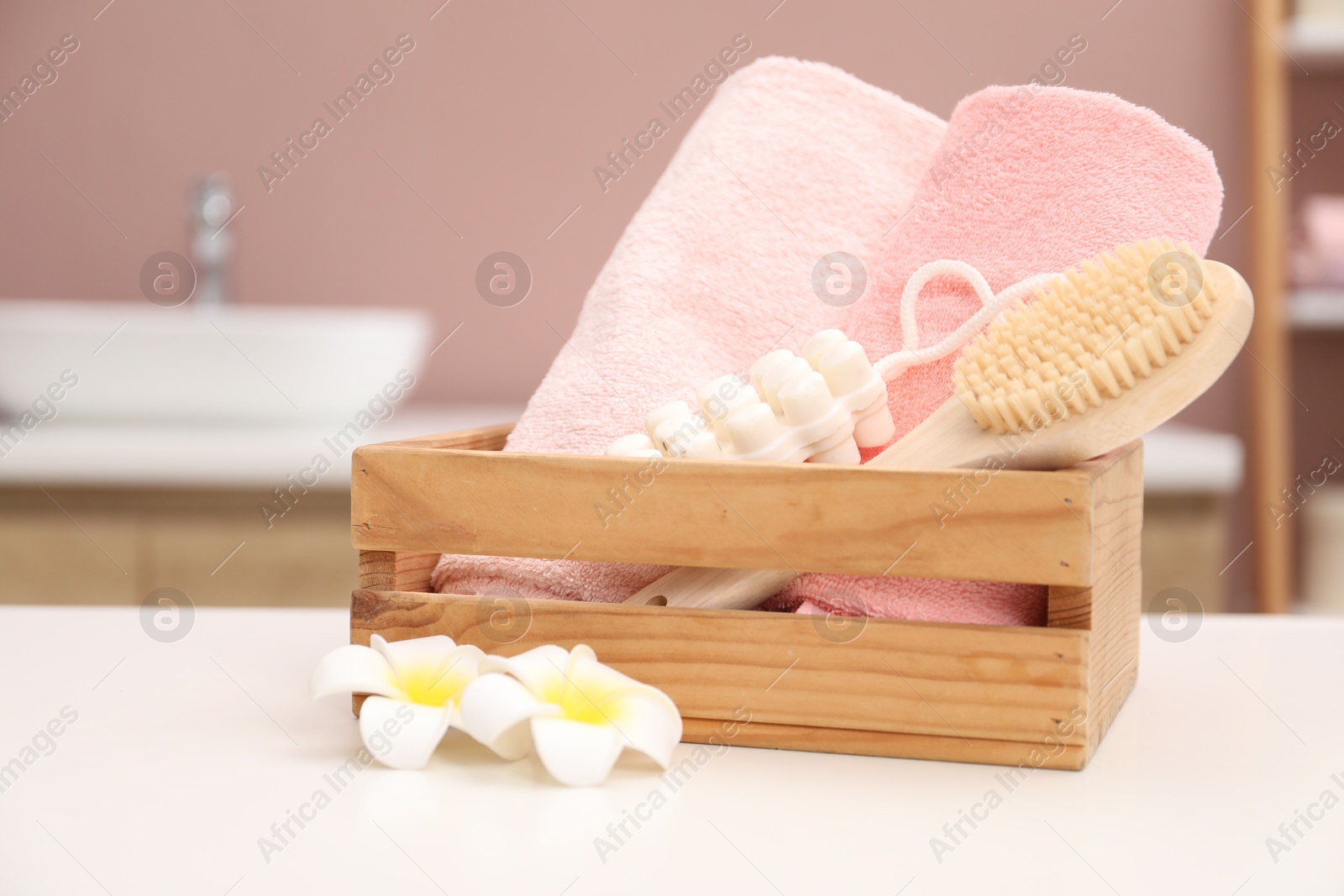 Colorful towels, brush, massage soap and plumeria flowers on white table indoors Photo of Colorful towels, brush, massage soap and plumeria flowers on white table indoors