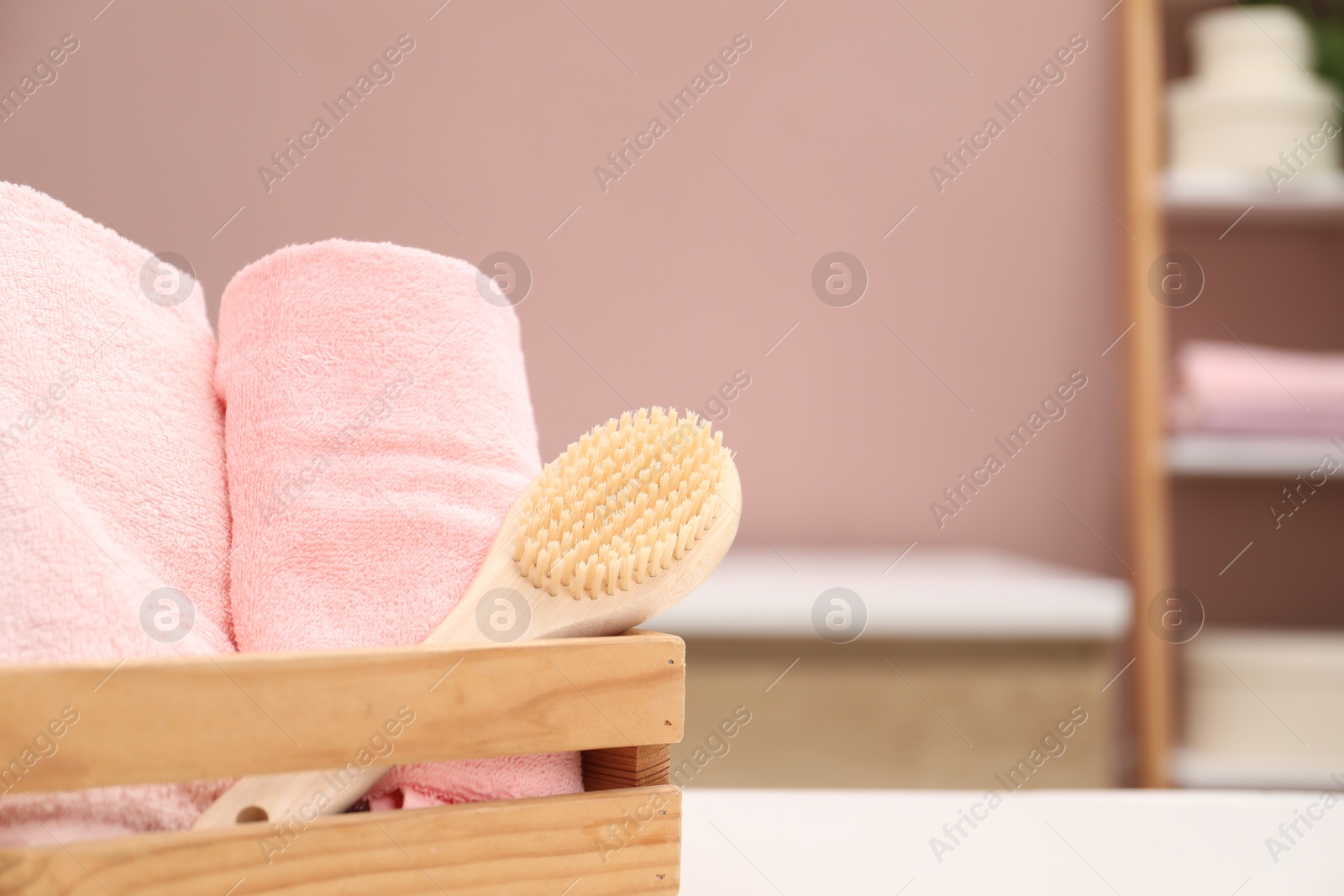 Colorful towels and brush in wooden basket on table indoors, closeup. Space for text Photo of Colorful towels and brush in wooden basket on table indoors, closeup. Space for text