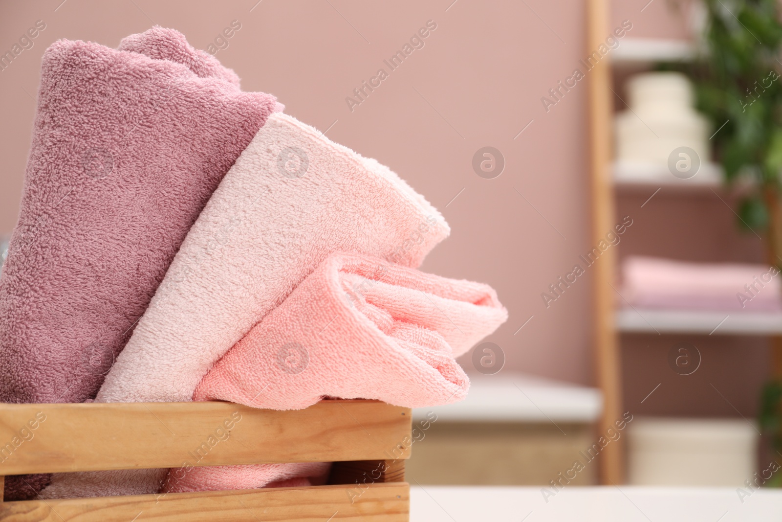 Colorful towels in wooden basket on table indoors, closeup. Space for text Photo of Colorful towels in wooden basket on table indoors, closeup. Space for text
