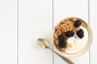 Photo of Tasty yogurt with granola and blackberries in bowl on white wooden table, top view. Space for text