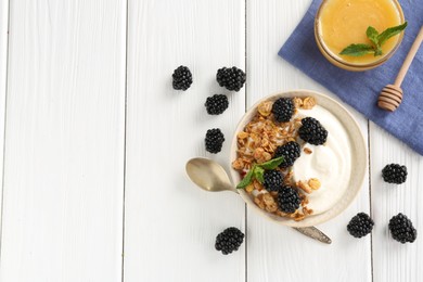 Photo of Tasty yogurt with granola, honey and blackberries in bowl on white wooden table, flat lay. Space for text