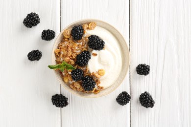 Photo of Tasty yogurt with granola and blackberries in bowl on white wooden table, flat lay