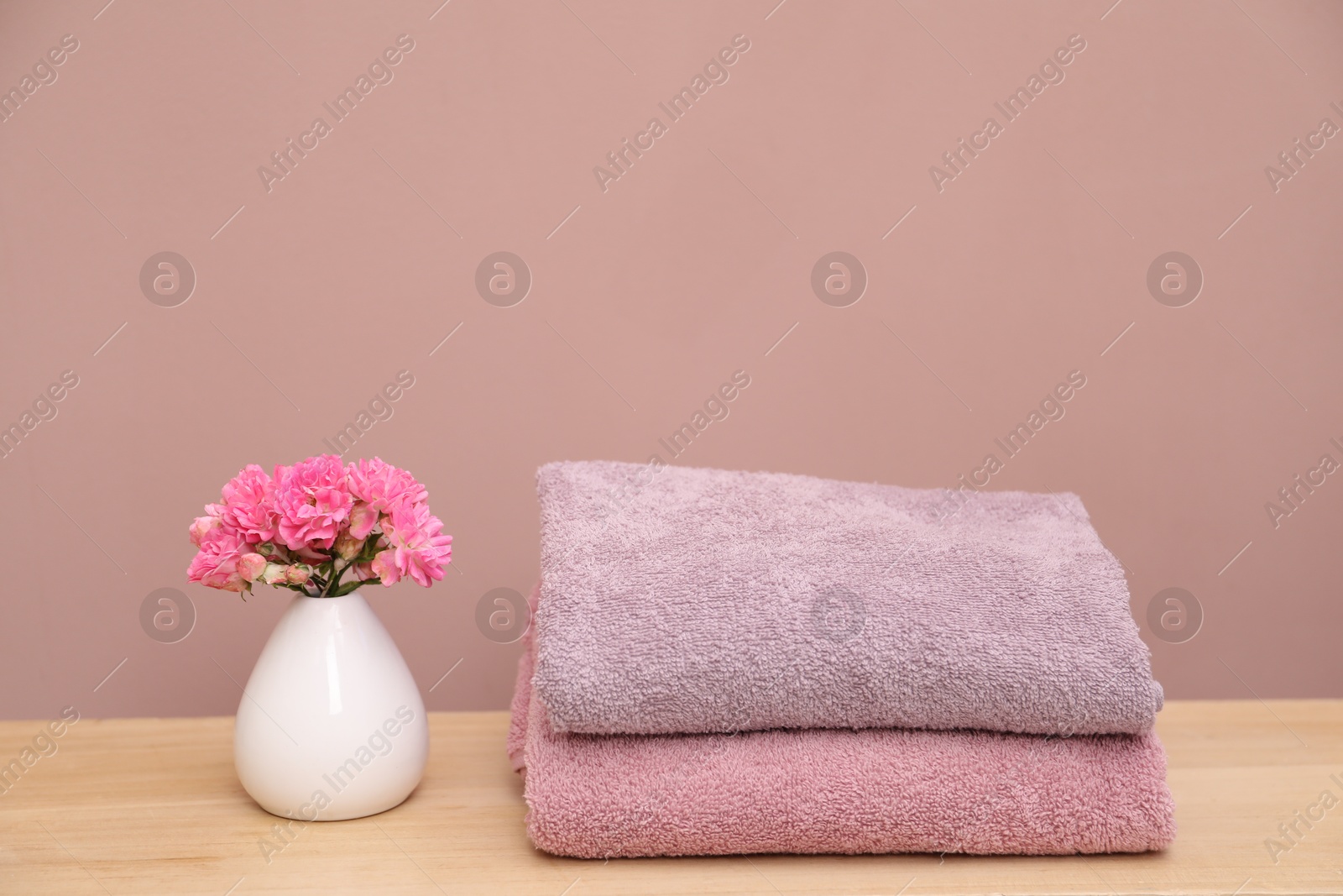Colorful towels and flowers on wooden table indoors Photo of Colorful towels and flowers on wooden table indoors