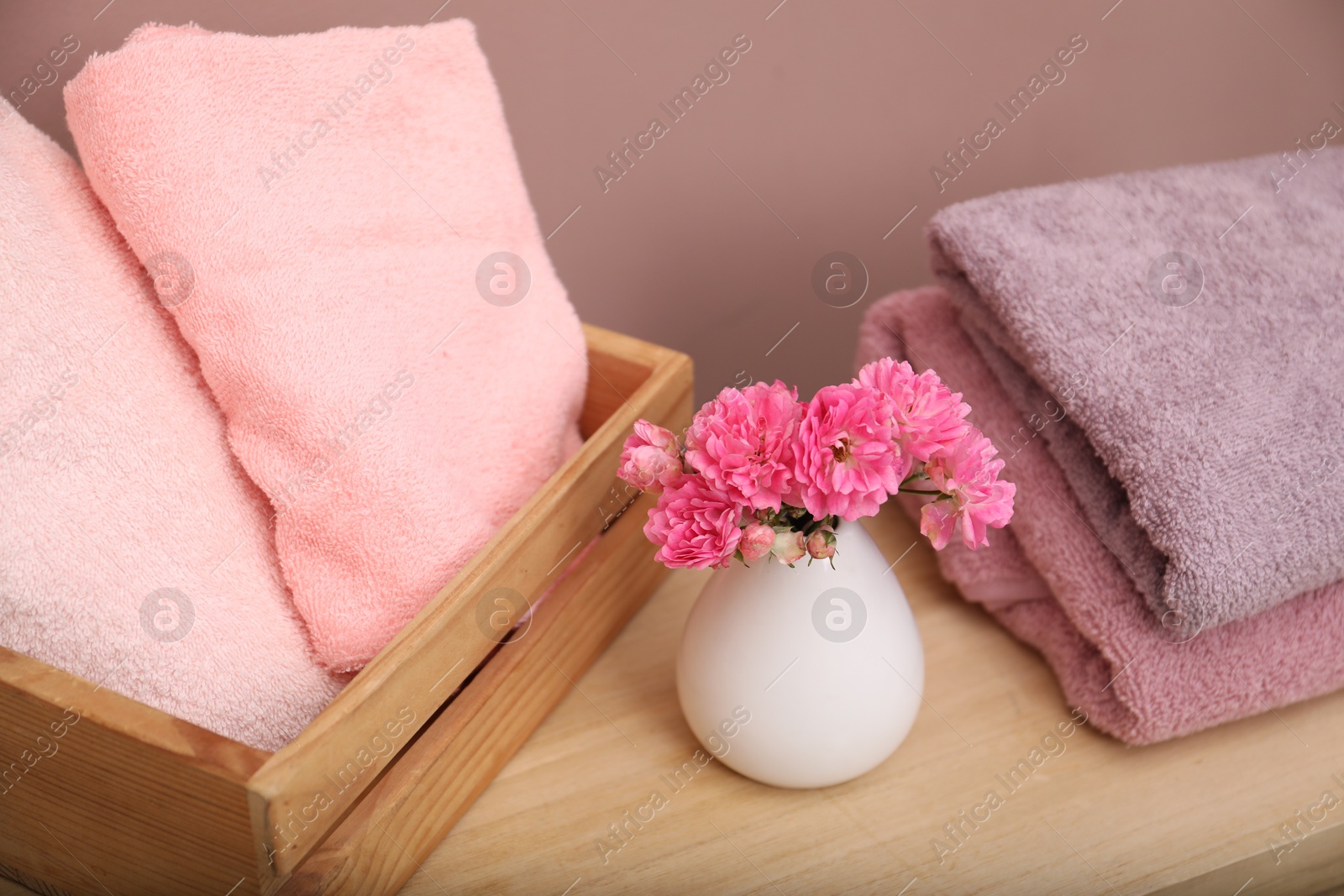 Different colorful towels and flowers on wooden table indoors, closeup Photo of Different colorful towels and flowers on wooden table indoors, closeup