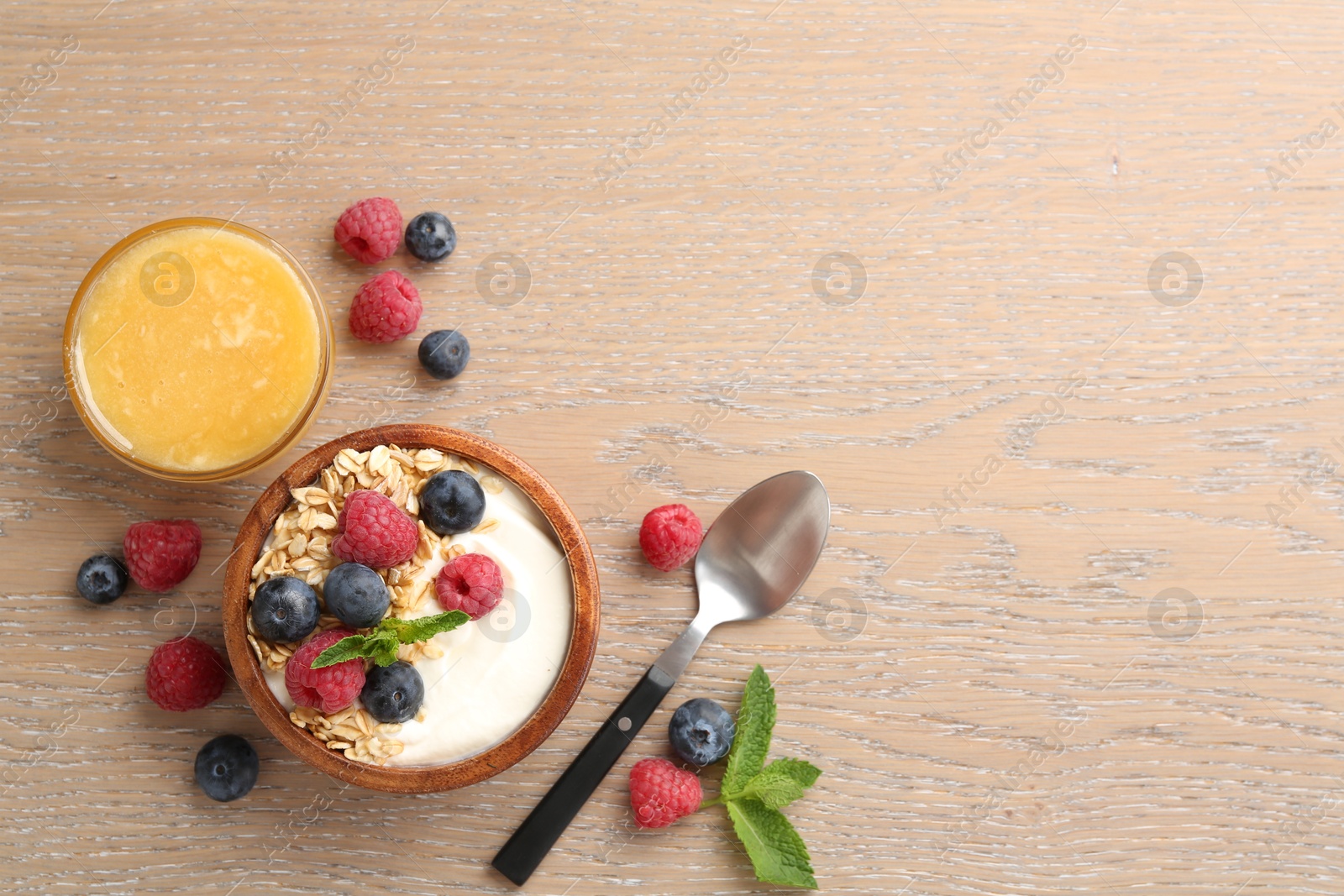 Tasty yogurt with granola, honey and berries in bowl on wooden table, flat lay. Space for text Photo of Tasty yogurt with granola, honey and berries in bowl on wooden table, flat lay. Space for text