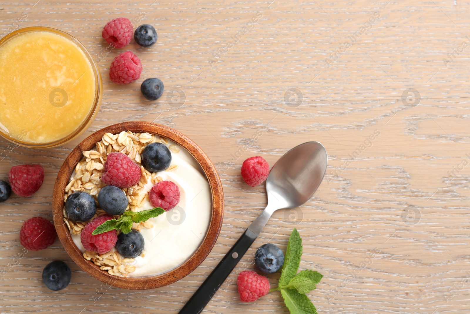 Tasty yogurt with granola, honey and berries in bowl on wooden table, flat lay. Space for text Photo of Tasty yogurt with granola, honey and berries in bowl on wooden table, flat lay. Space for text
