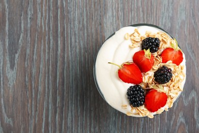 Photo of Tasty yogurt with granola and berries in bowl on wooden table, top view. Space for text