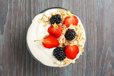Photo of Tasty yogurt with granola and berries in bowl on wooden table, top view