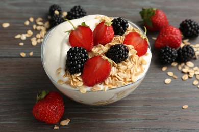 Photo of Tasty yogurt with granola and berries in bowl on wooden table, closeup