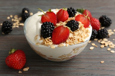 Photo of Tasty yogurt with granola and berries in bowl on wooden table, closeup