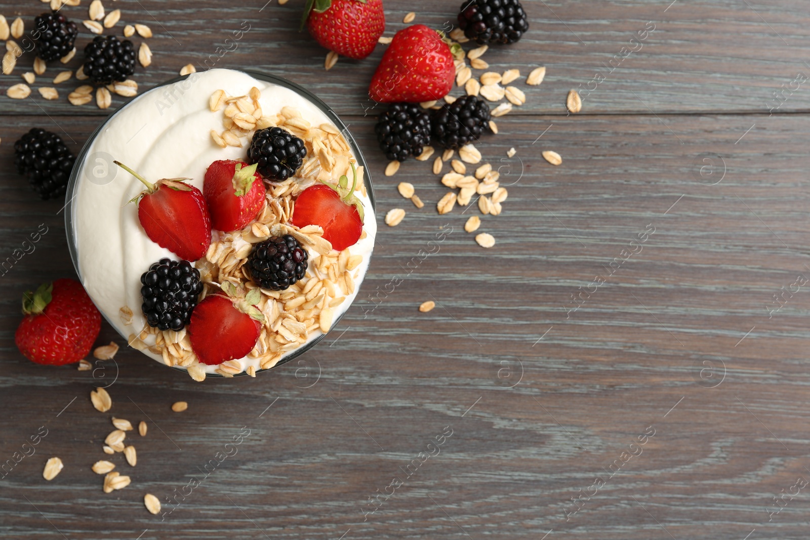 Tasty yogurt with granola and berries in bowl on wooden table, flat lay. Space for text Photo of Tasty yogurt with granola and berries in bowl on wooden table, flat lay. Space for text