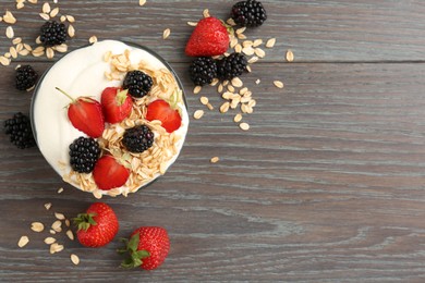 Photo of Tasty yogurt with granola and berries in bowl on wooden table, flat lay. Space for text