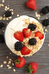 Photo of Tasty yogurt with granola and berries in bowl on wooden table, flat lay