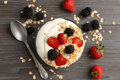 Photo of Tasty yogurt with granola and berries in bowl on wooden table, flat lay