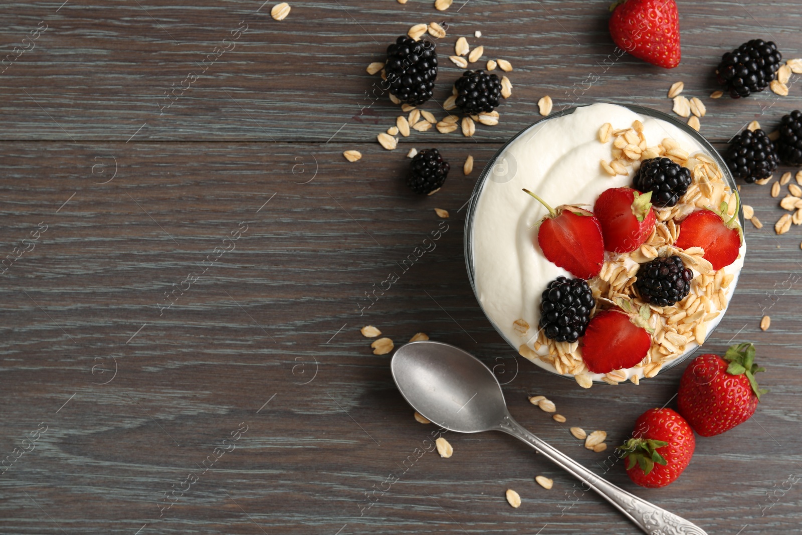Tasty yogurt with granola and berries in bowl on wooden table, flat lay. Space for text Photo of Tasty yogurt with granola and berries in bowl on wooden table, flat lay. Space for text