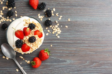 Photo of Tasty yogurt with granola and berries in bowl on wooden table, flat lay. Space for text