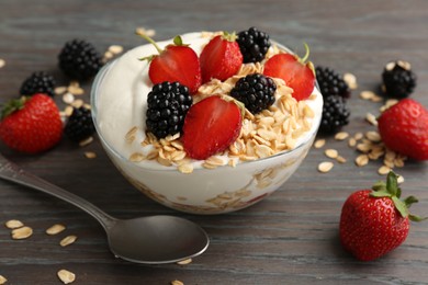 Photo of Tasty yogurt with granola and berries in bowl on wooden table, closeup