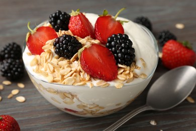 Photo of Tasty yogurt with granola and berries in bowl on wooden table, closeup