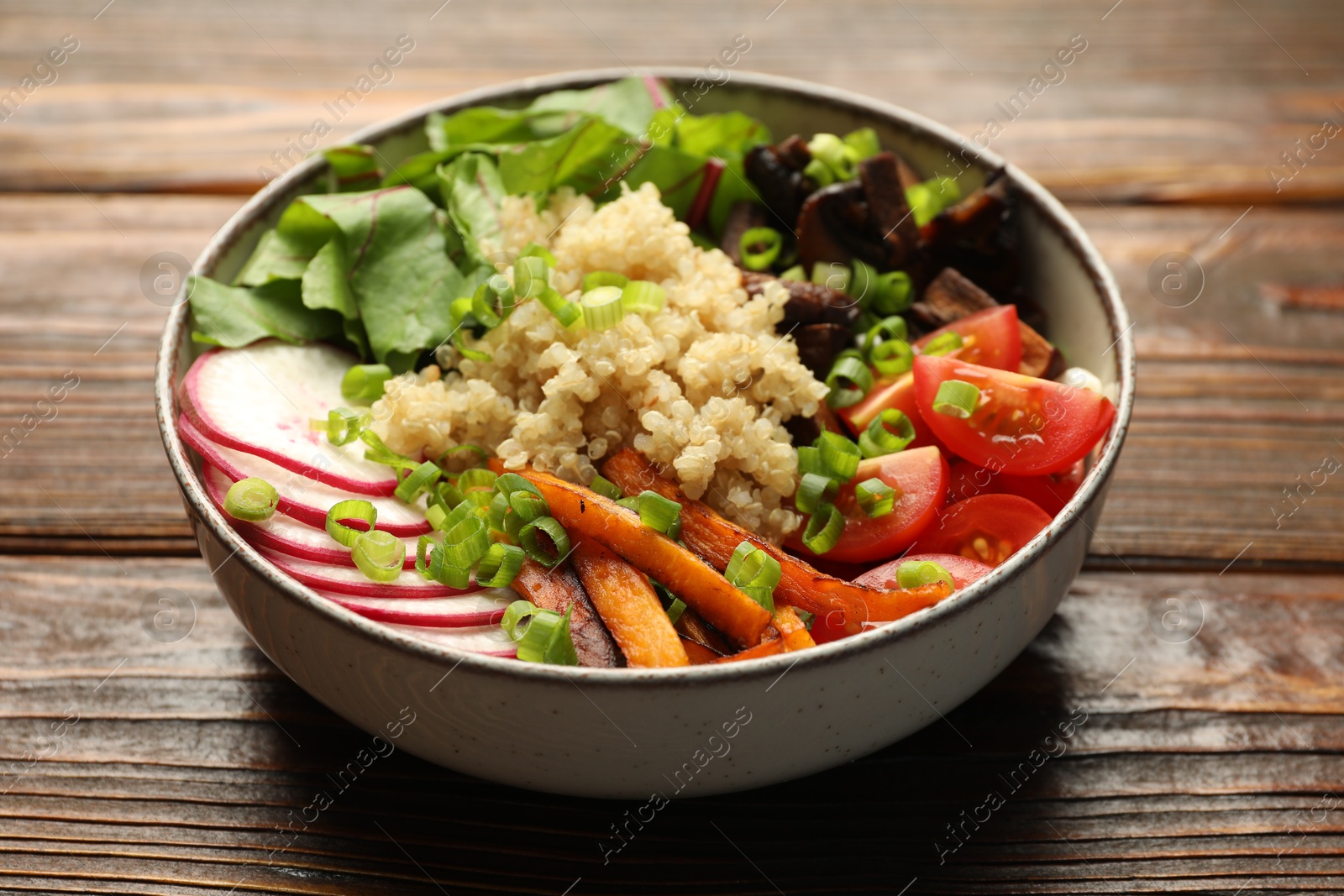 Photo of Healthy vegetarian food. Delicious Buddha bowl with quinoa, mushrooms and vegetables on wooden table, closeup