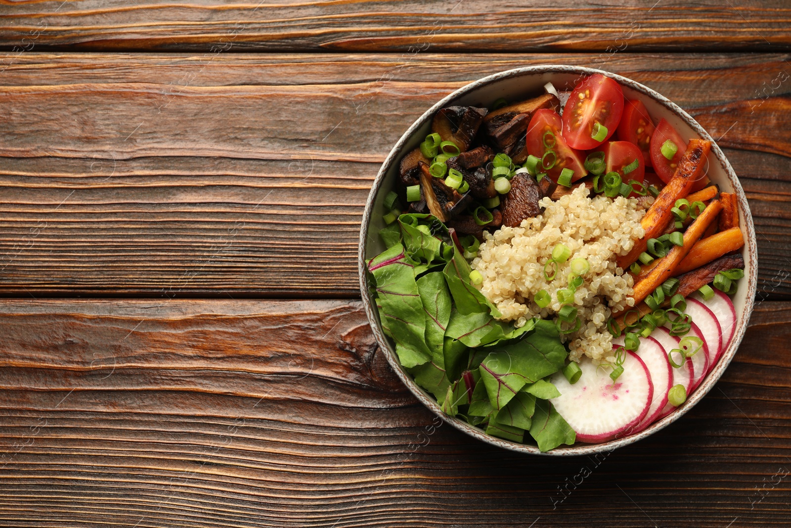 Photo of Healthy vegetarian food. Delicious Buddha bowl with quinoa, mushrooms and vegetables on wooden table, top view. Space for text