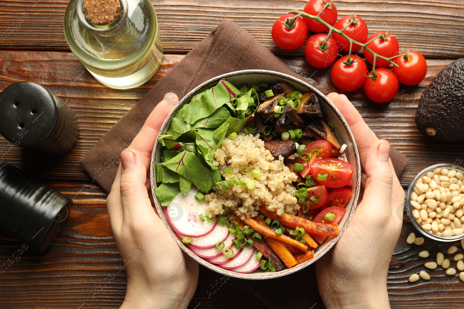 Healthy vegetarian food. Woman with delicious Buddha bowl and ingredients at wooden table, top view Photo of Healthy vegetarian food. Woman with delicious Buddha bowl and ingredients at wooden table, top view