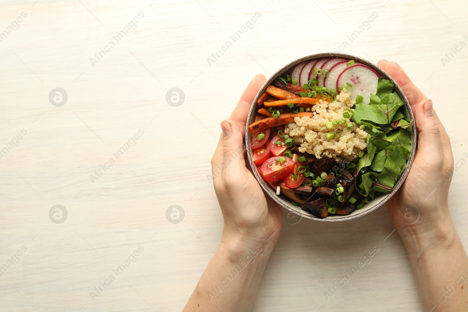 Healthy vegetarian food. Woman with delicious Buddha bowl at light wooden table, top view. Space for text Photo of Healthy vegetarian food. Woman with delicious Buddha bowl at light wooden table, top view. Space for text