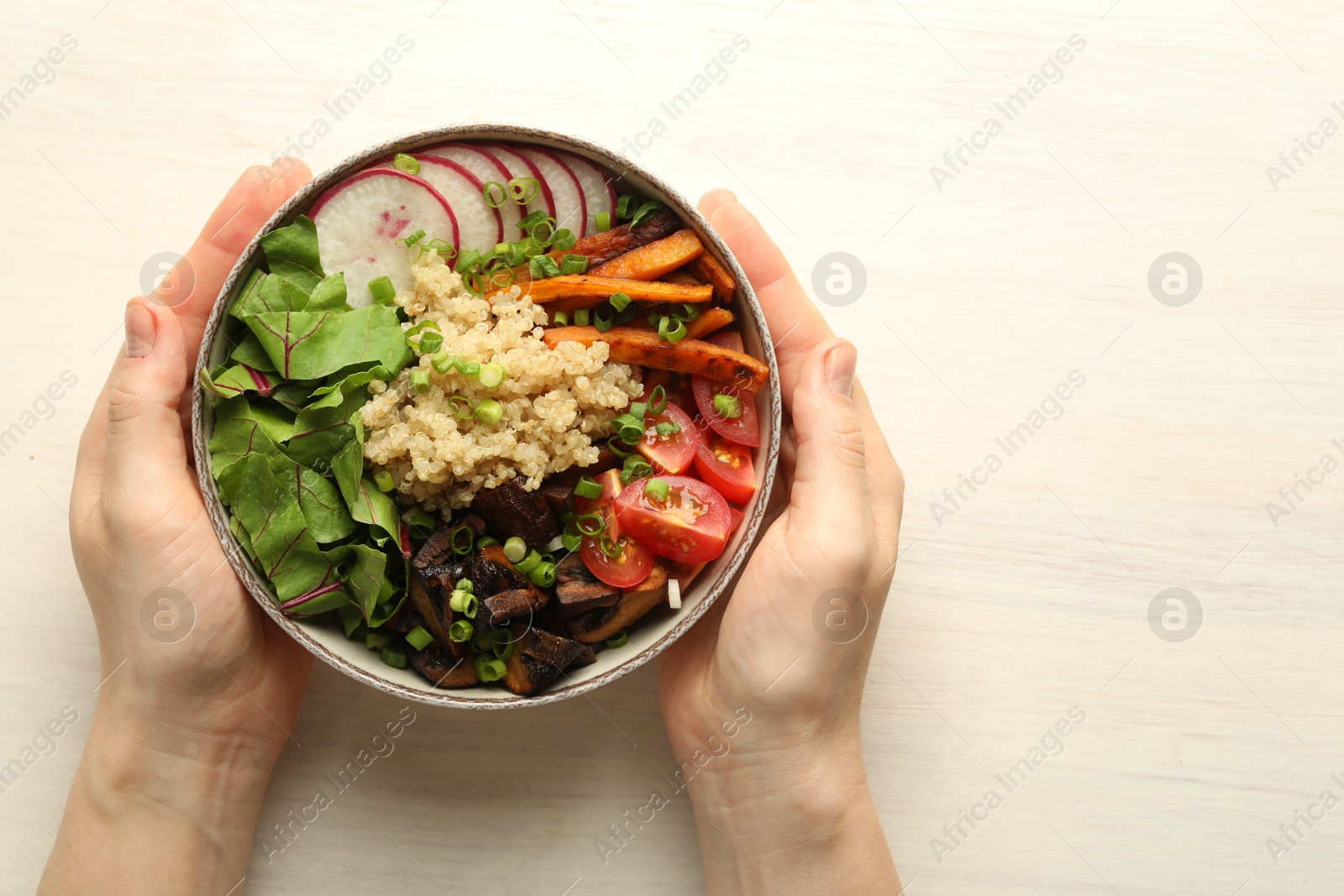 Healthy vegetarian food. Woman with delicious Buddha bowl at light wooden table, top view. Space for text Photo of Healthy vegetarian food. Woman with delicious Buddha bowl at light wooden table, top view. Space for text