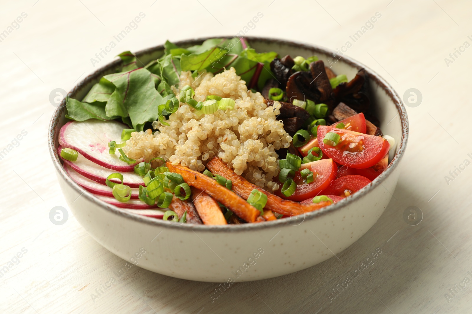 Healthy vegetarian food. Delicious Buddha bowl with quinoa, mushrooms and vegetables on light wooden table, closeup Photo of Healthy vegetarian food. Delicious Buddha bowl with quinoa, mushrooms and vegetables on light wooden table, closeup